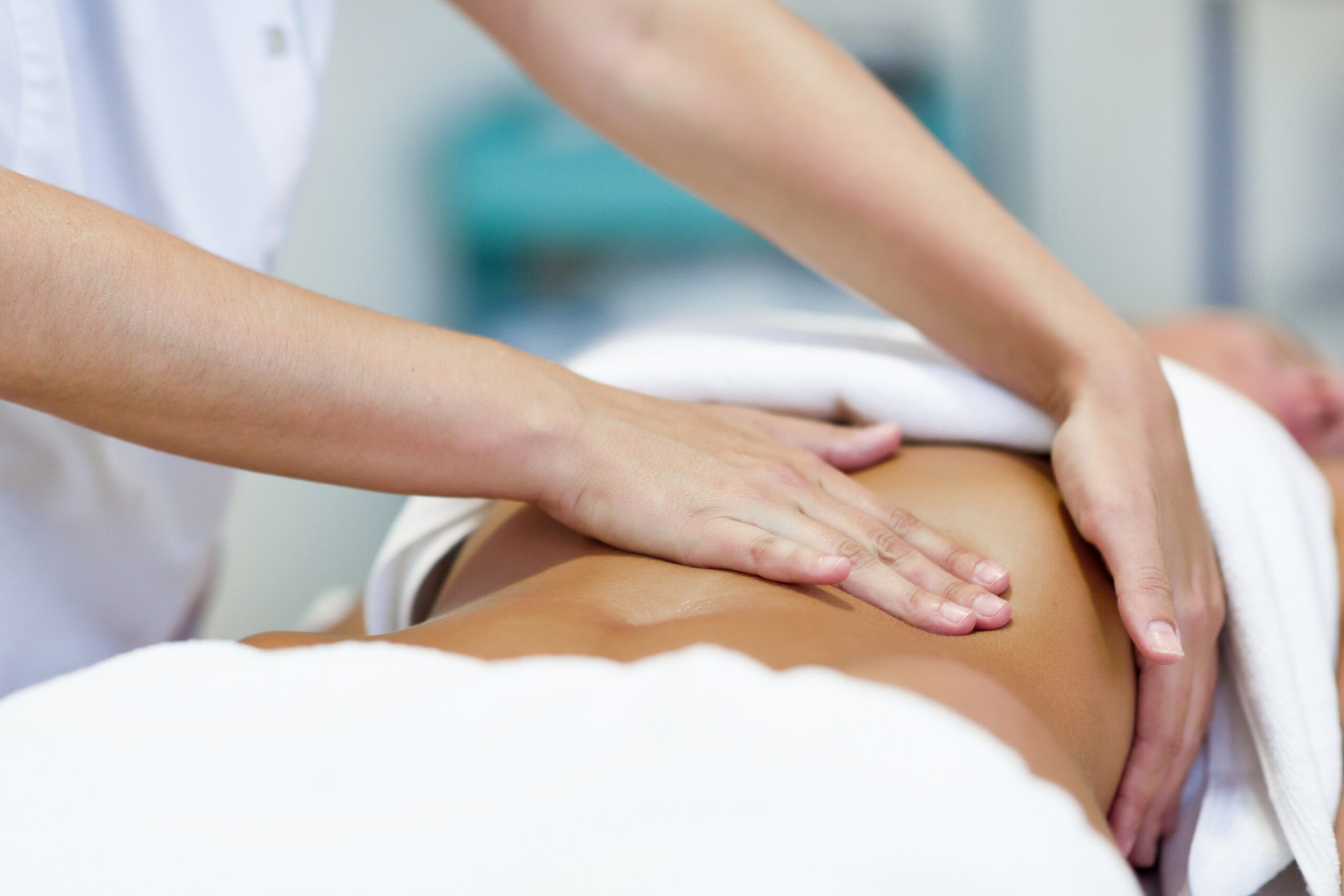 Female patient is receiving treatment by professional osteopathy therapist. Woman having abdomen massage in a physiotherapy center.